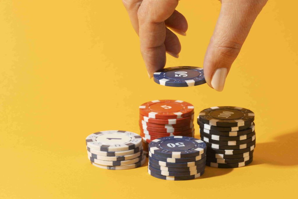 a hand putting a poker chip into a stack of poker chips